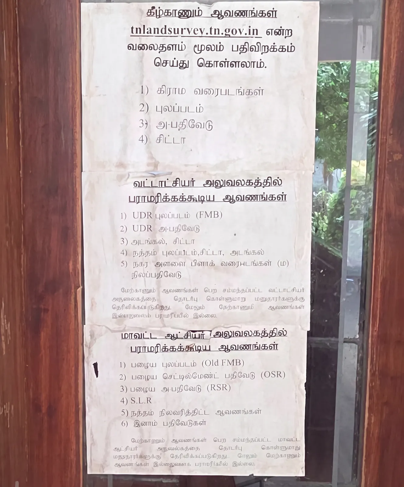 Government notice at a Tamil Nadu revenue office listing which land records can be downloaded from tnlandsurvey.tn.gov.in and which are held at the Taluk and District Collector offices